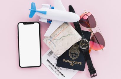 passport-map-tickets-toy-airplane-wrist-watch-mobile-phone-sunglasses-pink-background